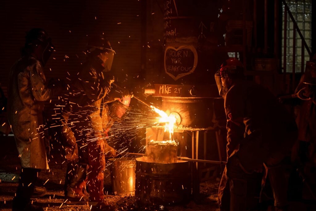 Metalworkers in protective gear handle molten metal at a foundry in Milwaukee, Wisconsin.