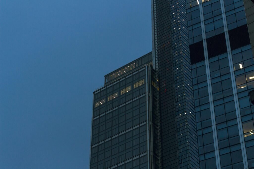 A towering skyscraper with illuminated windows at twilight, showcasing urban architecture.